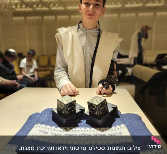נער עם תפילין עומד ליד שולחן עם תפילין נוספים